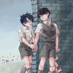 two young boys standing next to each other in front of a brick wall holding hands