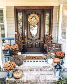 a front door decorated for fall with pumpkins and gourds on the steps