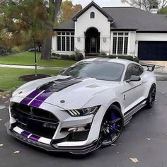 a white and purple mustang parked in front of a house