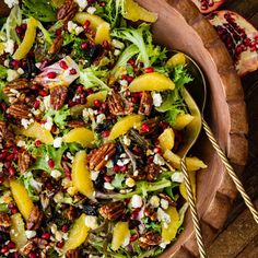 a salad with oranges, pecans and feta cheese in a wooden bowl