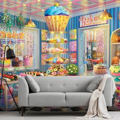 a room filled with lots of different types of cakes and donuts on display behind a gray couch