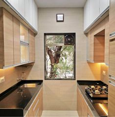 a narrow kitchen with black counter tops and wooden cabinets, along with an open window