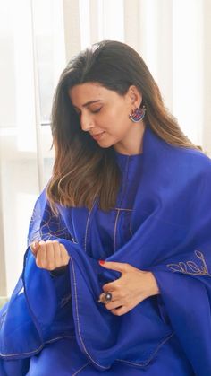 a woman sitting on top of a bed wearing a blue blanket