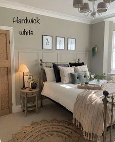 a bedroom with a white bed and some pictures on the wall next to each other