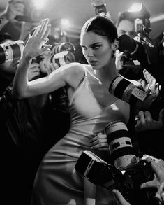 a black and white photo of a woman surrounded by photographers