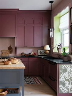 a kitchen with wooden floors and purple cabinets, along with an island in the middle