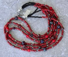 This appealing Necklace showcases 3 strands of Red Indonesian Glass Rondelle Beads. The Glass is opaque brick red in hue and approximately 3.5-by-4mm in dimension, with rounded edges and a matte finish. We've paired the Indonesian Glass with 7 complementary elements, including: Cranberry Czech Glass Faceted Rondelle Beads (8mm); Picasso Red Czech Tri-Cut Rounds (5-by-6mm); Shimmery Gray Glass Rondelle Beads (3-by-4mm); Polished Pyrite Rounds (4mm); Ruby Picasso Czech Glass Rounds (8mm); Red White Heart Glass Rondelle Beads (6.5-by-7mm); Translucent Red Cathedral-Cut Glass Rounds (5.5mm). These elements add color depth, translucency and subtle sparkle. At the top of the Necklace the Indonesian Glass transitions to 3mm Black Glass Seed Beads, streamlining the silhouette and ensuring a comfor Red Rondelle Necklace With Polished Beads, Southwestern Style Adjustable Red Necklace, Red Cathedral, Unique Red Multi-strand Beaded Necklaces, Red Southwestern Hand-strung Beaded Necklaces, Red Multi-strand Jewelry With Polished Beads, Southwest Design, Black Seed, Southwest Jewelry