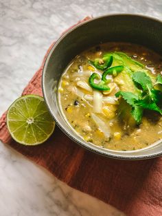 a bowl filled with soup next to a slice of lime