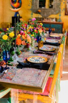 the table is set with colorful flowers and place settings for four people to sit at