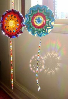 two decorative items hanging from a window sill with sunlight shining through the windowsill