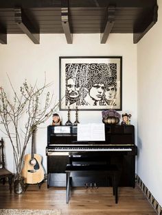 a black piano sitting in the middle of a living room next to a vase with flowers