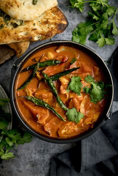 a pan filled with chicken curry and garnished with cilantro