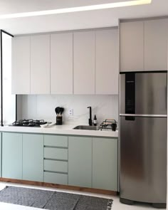 a modern kitchen with stainless steel appliances and white cabinets, along with a rug on the floor