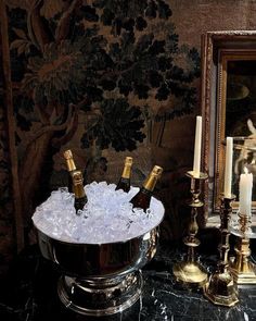 an ice bucket with two bottles of champagne in it next to candles and a mirror