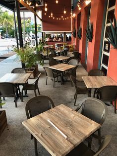 an empty restaurant with tables and chairs on the outside, lights hanging from the ceiling