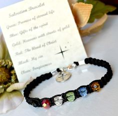 a bracelet with four different colored stones on it next to a card and flower bouquet