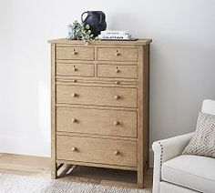 a wooden dresser sitting next to a white chair