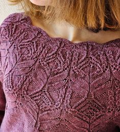 a close up of a woman wearing a sweater with an intricate design on the back