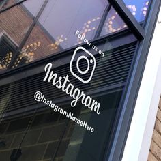 an instagram logo on the side of a storefront window in front of a brick building