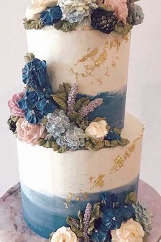 a three tiered cake with blue and white frosting flowers on the bottom layer