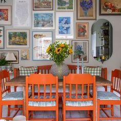 a dining room table with chairs and pictures on the wall