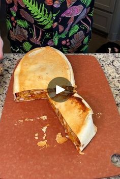 a person cutting up a sandwich on top of a cutting board next to a knife