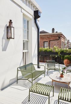 an outdoor patio with chairs, table and potted plant on the side of the house