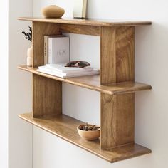 two wooden shelves with books and vases on each shelf, one holding a book