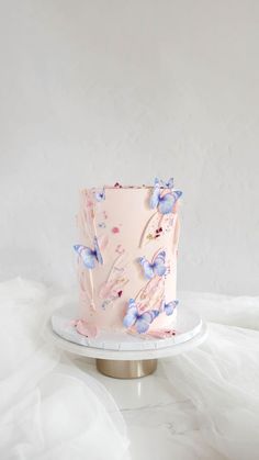 a pink and blue cake with butterflies on it sitting on top of a white plate