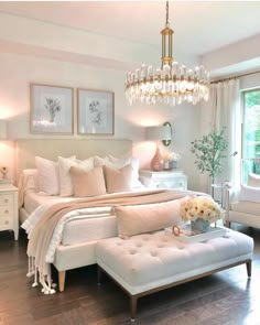 a bedroom with white furniture and chandelier hanging from the ceiling, along with pictures on the wall