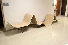 two wooden benches sitting next to each other on the floor in an empty room with white walls