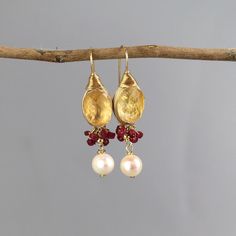 These rich and glamorous Ronit earrings are bezel set with a sunny citrine gemstone and a dainty cluster of natural rubies. A single pearl dangles down gently. Wire wrapped gold filled details give these earrings a very unique and artistic look. A total statement piece with lots of elegance, you'll have lots of fun wearing these!   Measurements: Length (including hook): approx. 4.5cm  Citrine: 10x14mm Materials: Stone: citrine, ruby, pearl  Metal: sterling silver bezel and gold filled Hook: gold filled Citrine Properties:  Happiness, Prosperity, Generosity, Creativity, Pleasure, Protection, Strength.   Since I use natural gemstones, each jewel is unique and therefore there are subtle differences in color and form. TURNAROUND TIME & SHIPPING  This piece will be made within 7 business days f Gold Briolette Pearl Gemstone Earrings, Yellow Gold Teardrop Pearl Earrings With Gemstone, Gemstone Dangle Pearl Earrings For Anniversary, Dangle Pearl Earrings With Gemstone For Anniversary, Gold Gemstone Pearl Earrings For Wedding, Briolette Earrings With Gemstone Accents For Wedding, Briolette Earrings With Natural Stones For Anniversary, Briolette Natural Stones Anniversary Earrings, Gold Pearl Gemstone Earrings For Anniversary