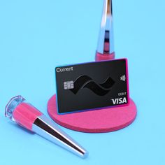 a credit card sitting on top of a pink holder next to a pair of scissors