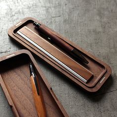 two wooden trays with pens and pencils in them