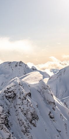 a person on skis in the middle of a snowy mountain range with mountains behind them