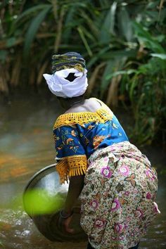 a woman is standing in the water with a bucket