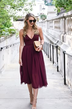 a woman in a purple dress is walking down the street with her hand on her hip