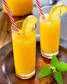 two glasses filled with orange juice and garnished with straws on a plate