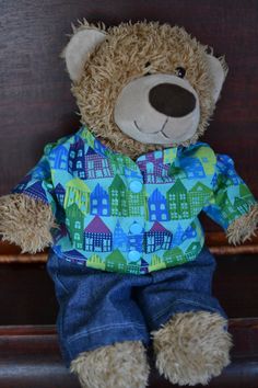 a brown teddy bear sitting on top of a wooden bench