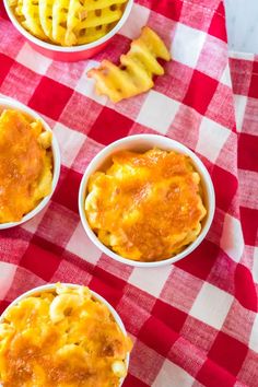 three bowls filled with macaroni and cheese on top of a checkered table cloth