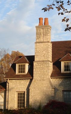 a large brick house with two chimneys on the top and one at the end of the roof