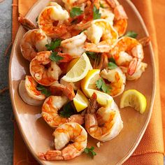 a plate with shrimp, lemon and parsley on it