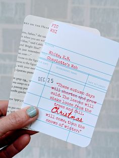 a person holding up a piece of paper with writing on it that says christmas written in red