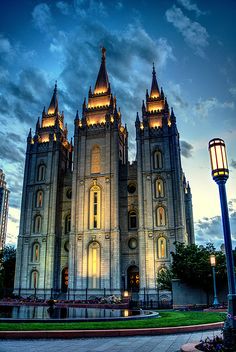 a large cathedral lit up at night with street lights on the side and clouds in the sky