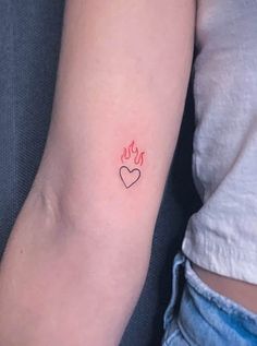 a woman's arm with a small red heart tattoo on the left side of her arm