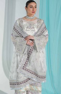 Heavily Embellished Silver Pakistani Long Kameez Sharara Wedding Dress is a traditional and refined Pakistani Wedding Dress with exquisite adornments on it causing it unpaired in its grace and beauty. The lovely finish of this attire and intricate golden details count more toward the luxuries of this Fancy Sharara Kameez. Organza Kameez: This Sliver White Organza Kameez comes in a beautiful kameez in premium quality raw organza. This kameez is decorated with breathtaking embellished patterns acc Pakistani Boutique, Pakistani Designer Clothes, Embellished Shirt, Pakistani Wedding Dress, Unstitched Dress Material, Readymade Saree, Embroidered Chiffon, Embroidered Organza, Pakistani Wedding Dresses