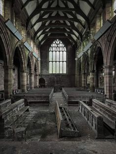 an old church with pews in the middle and stained glass windows on both sides