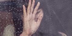 a woman's hands are seen through the rain - soaked window