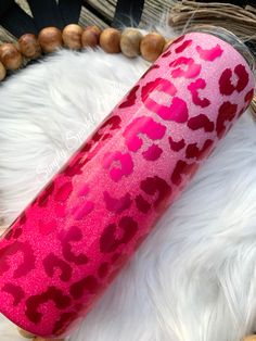 a pink and red leopard print tumbler sitting on top of a white fur rug