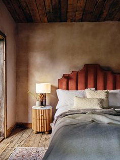 a bed sitting next to a lamp on top of a wooden table in a bedroom